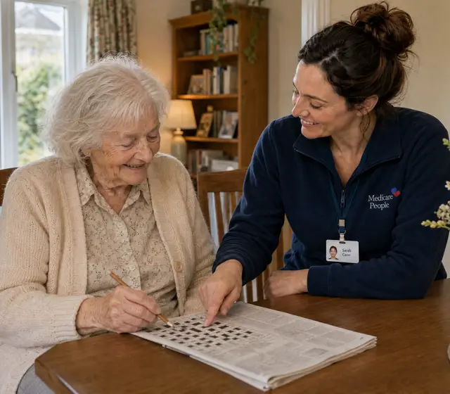 Live-in carer helping an older woman with a newspaper crossword at the dining table Live-in carer helping an older woman with a newspaper crossword at the dining table
