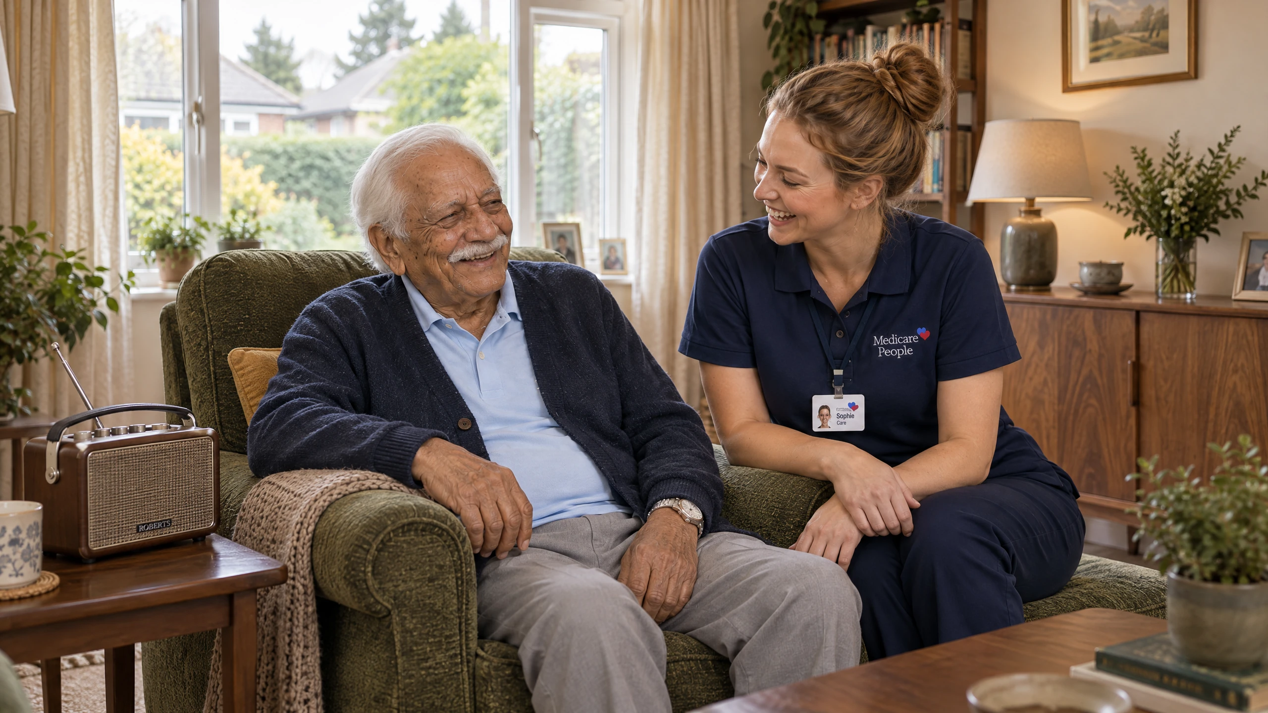 Live-in carer relaxing and chatting with an older man in his living room