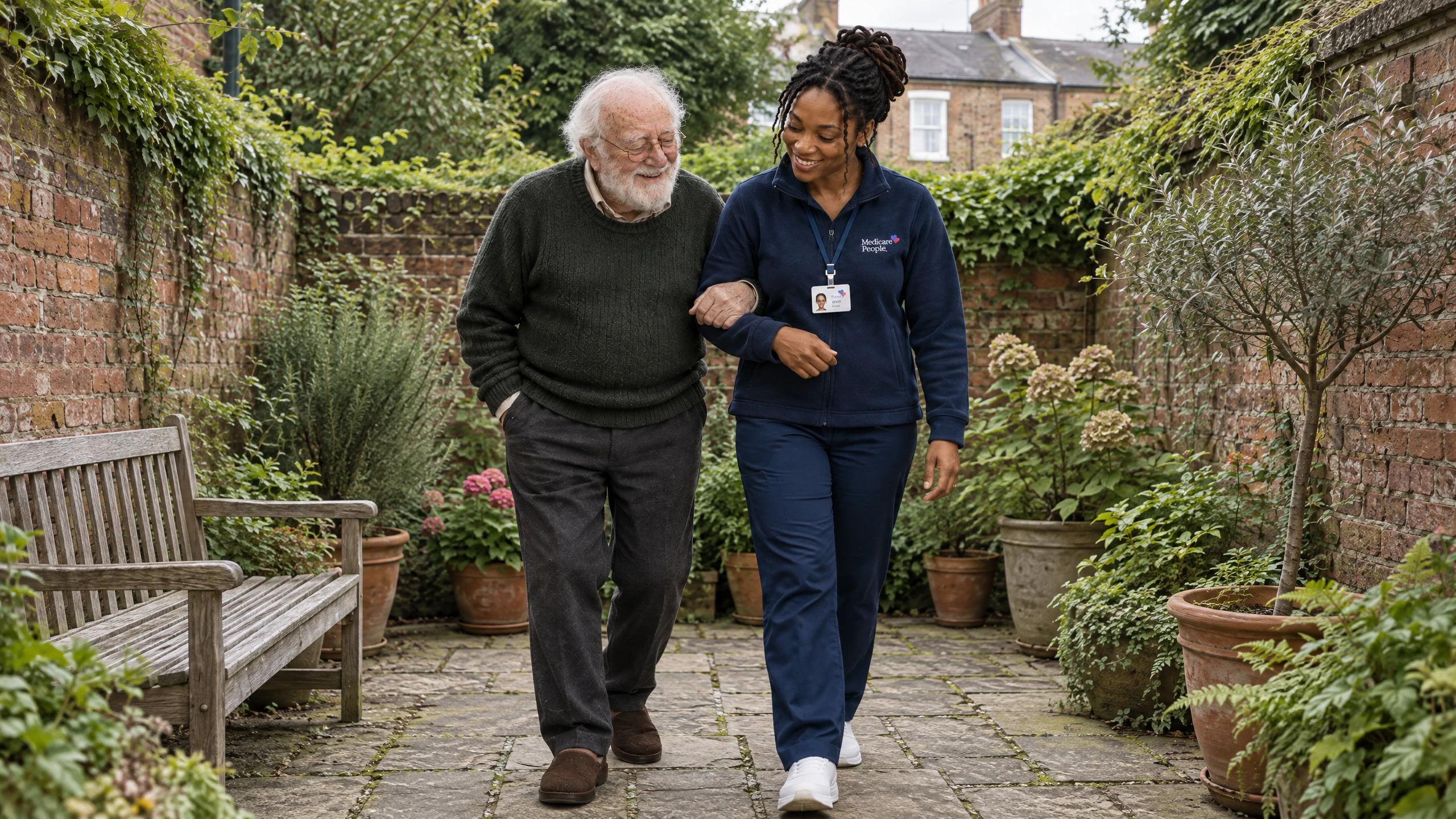 Live-in carer walking with an older man through his walled courtyard garden in Guildford